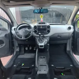 Wnętrze samochodu Citroen Berlingo z wyjętymi fotelami, widoczne czarne dywaniki podłogowe i elementy demontażu, przygotowane do czyszczenia.