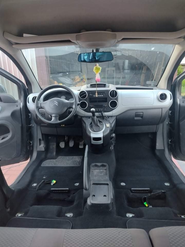 Wnętrze samochodu Citroen Berlingo z wyjętymi fotelami, widoczne czarne dywaniki podłogowe i elementy demontażu, przygotowane do czyszczenia.