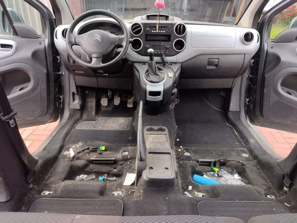 Wnętrze samochodu Citroen Berlingo przed czyszczeniem, widoczne zdemontowane elementy i zabrudzona podłoga.