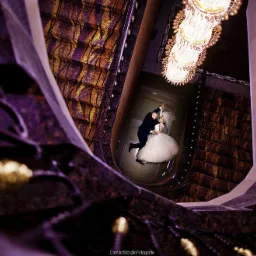 Para młoda w tańcu, uchwycona z góry w eleganckim wnętrzu z żyrandolem, widok z perspektywy spiralnych schodów z bogatym zdobieniem.