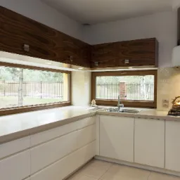 Jasna kuchnia z kremowymi szafkami i drewnianymi szafkami górnymi, duży blat roboczy z oknami z widokiem na ogród, nowoczesny okap nad płytą gazową.