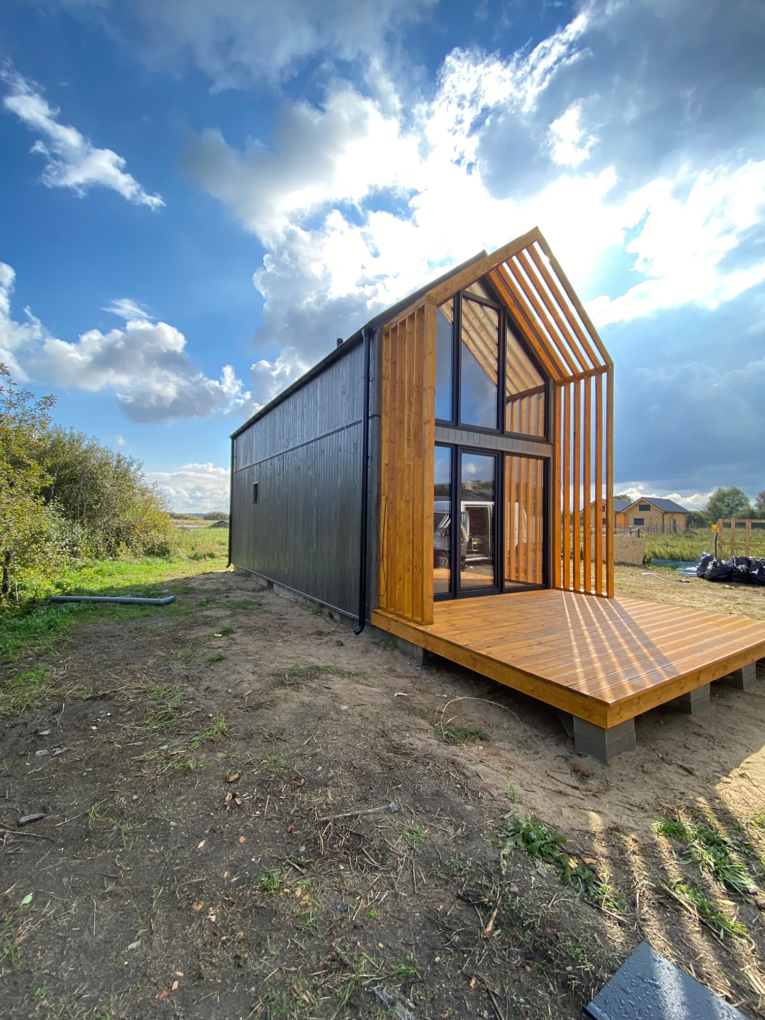 Nowoczesny dom modułowy z drewnianą konstrukcją szkieletową i tarasem, widok z zewnątrz w słoneczny dzień.