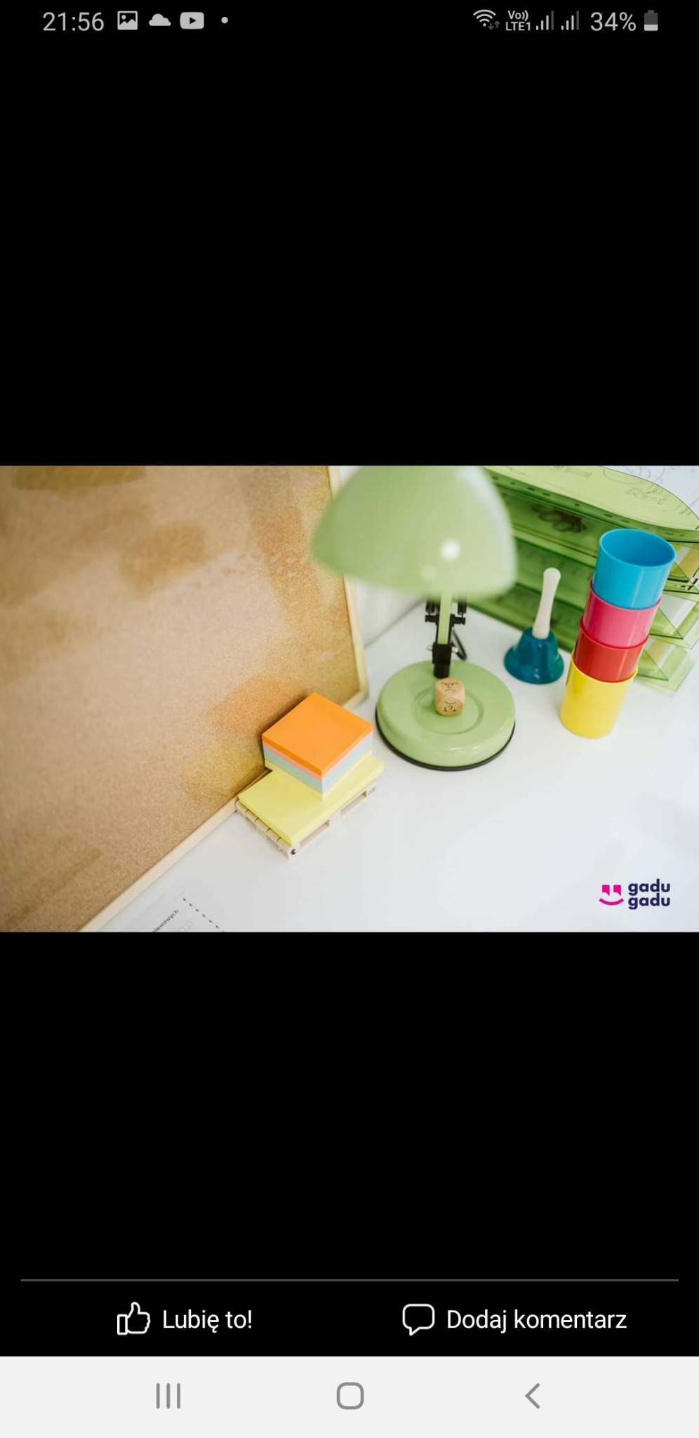 Biurko z zieloną lampką, korkową tablicą, kolorowymi karteczkami samoprzylepnymi i kubeczkami do ćwiczeń oddechowych, kostka do gry leży na lampce.