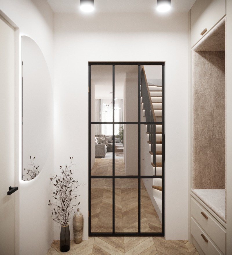 Nowoczesny przedpokój z czarną, przeszkloną ścianką działową prowadzącą do salonu, drewniana podłoga w jodełkę, okrągłe lustro z podświetleniem i dekoracyjna gałązka w wazonie.