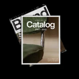 Katalog produktowy z okładką przedstawiającą fragment krzesła w odcieniach zieleni, leżący na innym katalogu z widocznym fragmentem napisu 'Brand' w czarno-białej kolorystyce.
