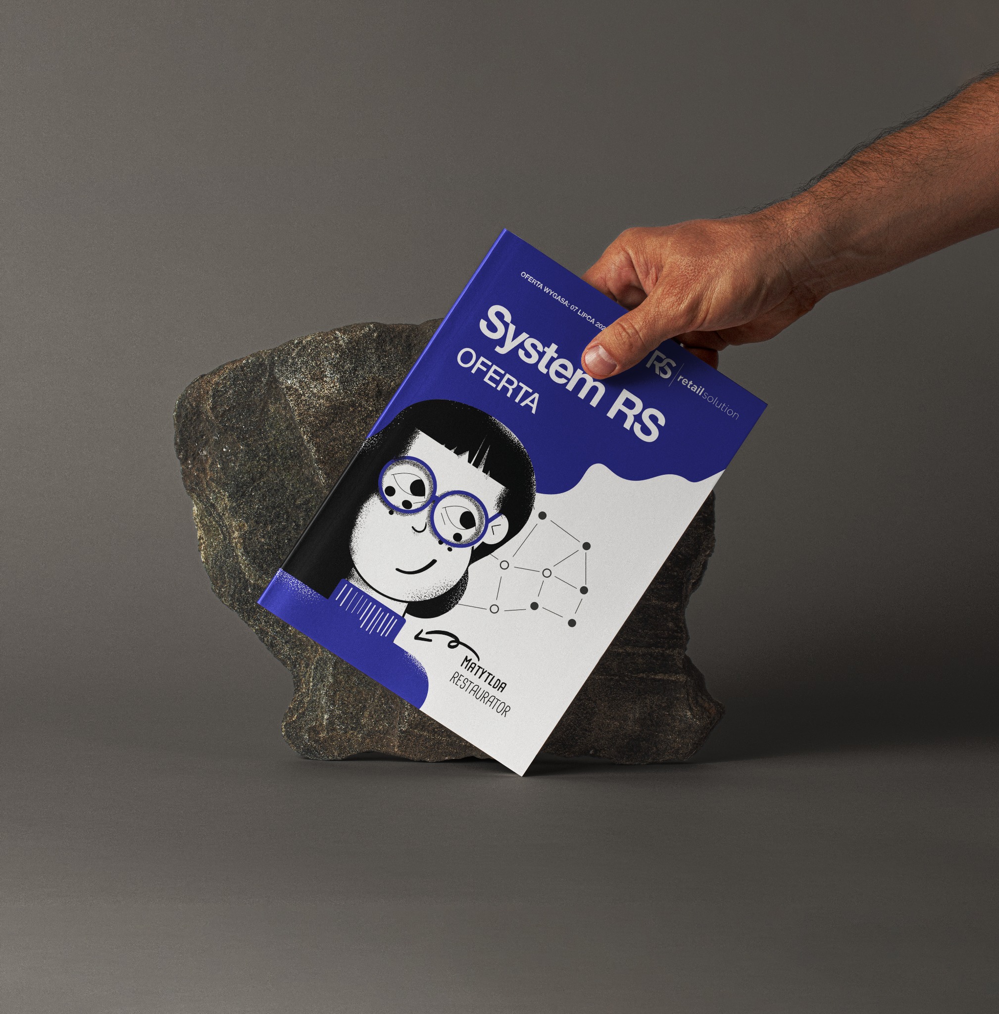 Męska dłoń prezentuje ulotkę reklamową 'System RS Oferta' z ilustracją postaci w okularach i siecią połączeń, opartą o szary kamień na szarym tle.