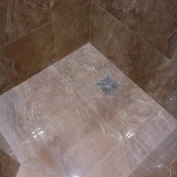 BUDTEAM Roman Taran - Wykończona kabina prysznicowa z brązowymi, marmurkowymi płytkami ceramicznymi i odpływem liniowym w rogu.