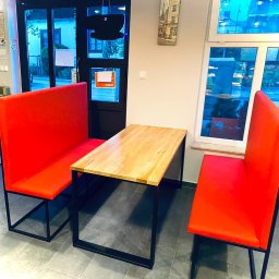 6 - Stół z jasnego drewna i dwie czerwone ławki z czarnymi metalowymi nogami w pomieszczeniu z oknem.