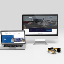 Prezentacja strony internetowej firmy transportowej Domar na laptopie i monitorze, słuchawki obok.