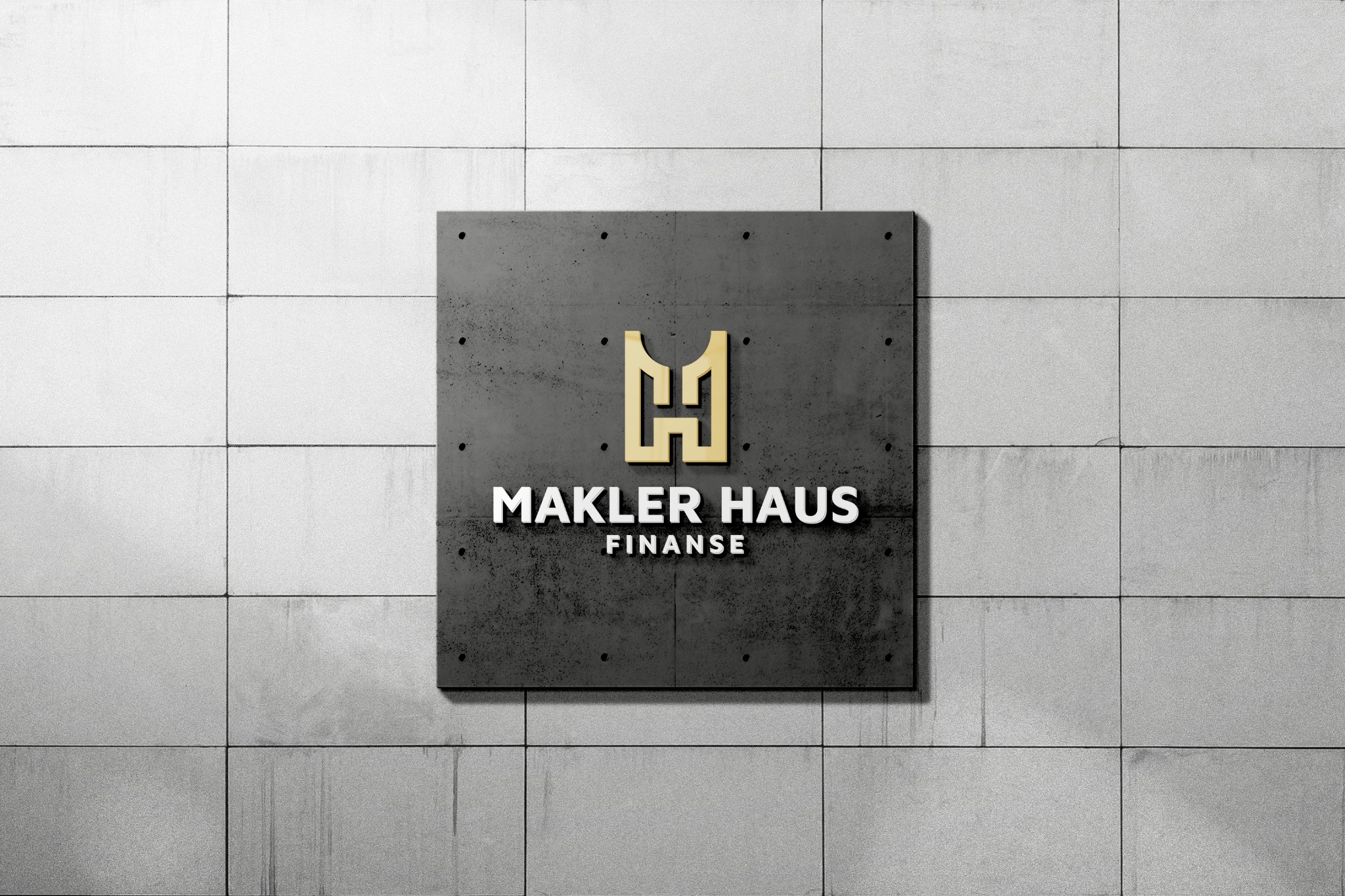 Tablica z logo 'Makler Haus Finanse' w kolorze złotym, umieszczona na szarej, teksturowanej ścianie z płyt betonowych.