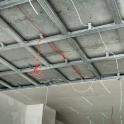 Stelaż sufitu podwieszanego z widocznymi przewodami elektrycznymi przed montażem płyt gipsowo-kartonowych.