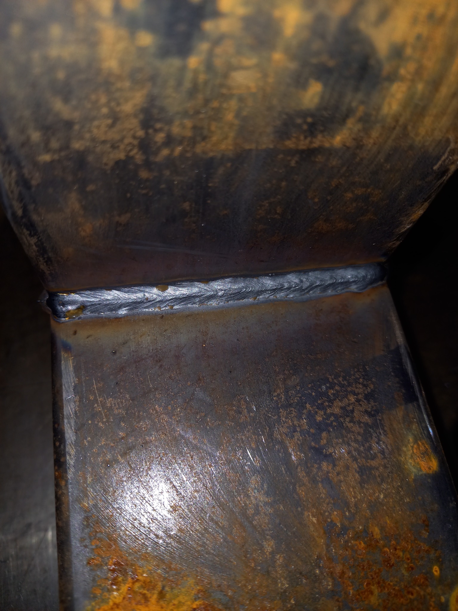 Spoina łącząca dwa elementy metalowe o rdzawym nalocie, widoczna linia spawu z charakterystycznym wzorem.