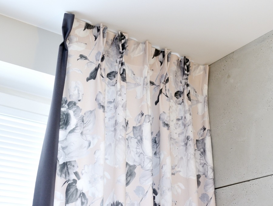 Elegancka zasłona w kwiaty z ciemnoszarym bokiem, zawieszona na karniszu w nowoczesnym wnętrzu.