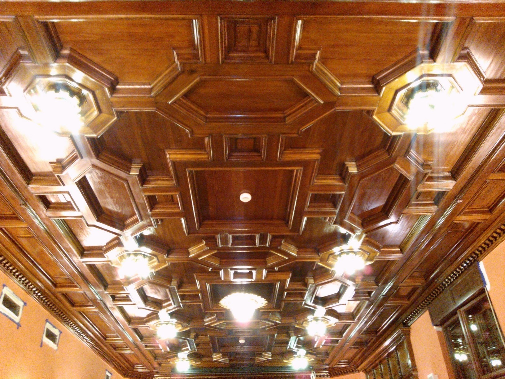 Dekoracyjny, kasetonowy sufit z drewna z wbudowanymi lampami, oświetlony od dołu, widok pod kątem.