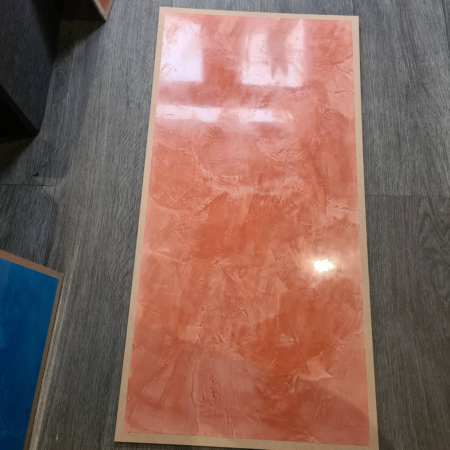 Panel z efektem dekoracyjnym w odcieniach terakoty, prezentujący fakturę przypominającą naturalny kamień, ułożony na podłodze imitującej drewno.