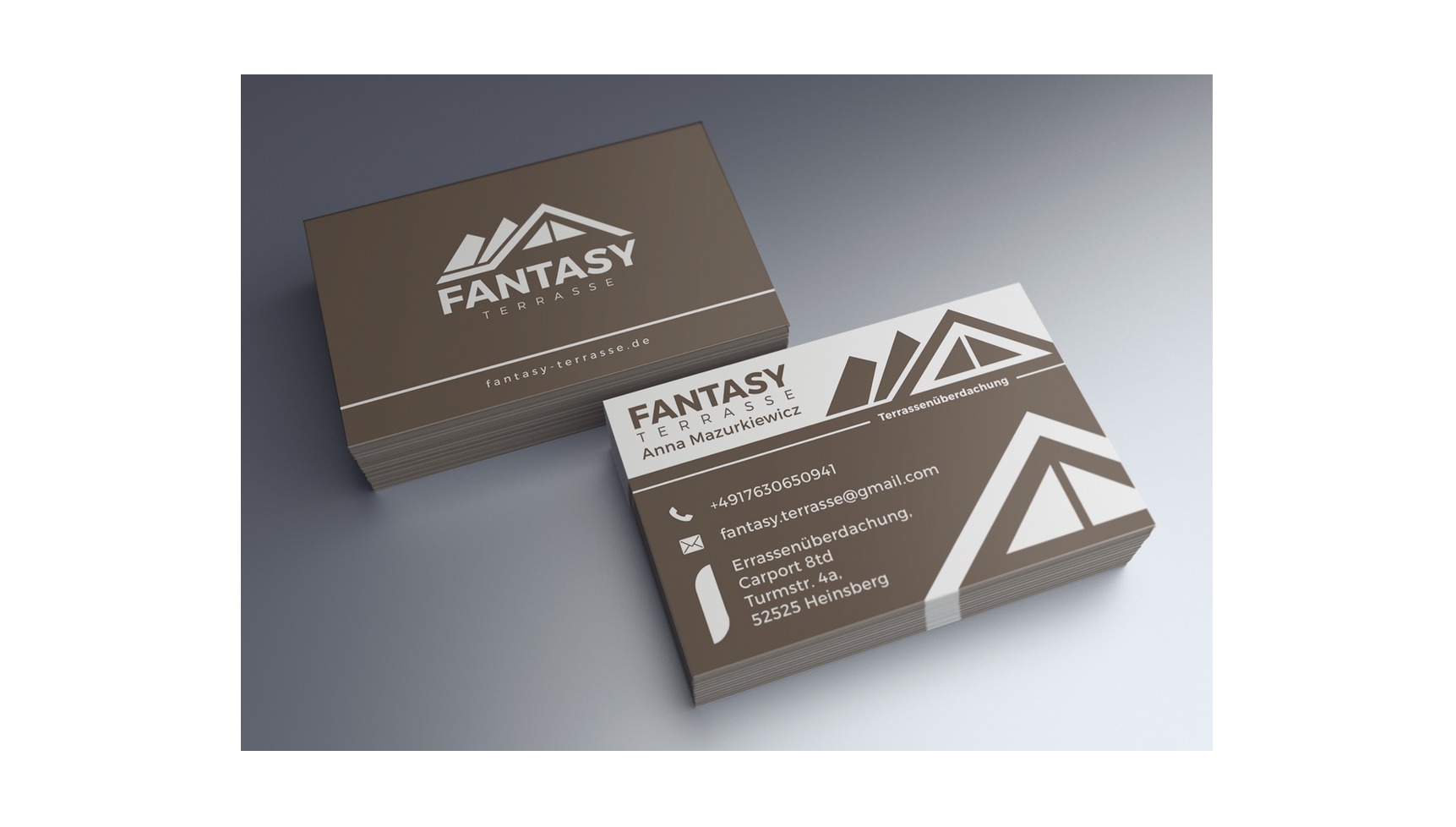 Stos wizytówek firmy Fantasy Terrasse w odcieniach brązu i bieli, prezentujący logo z motywem dachu i dane kontaktowe, ułożony na gładkim, szarym tle.