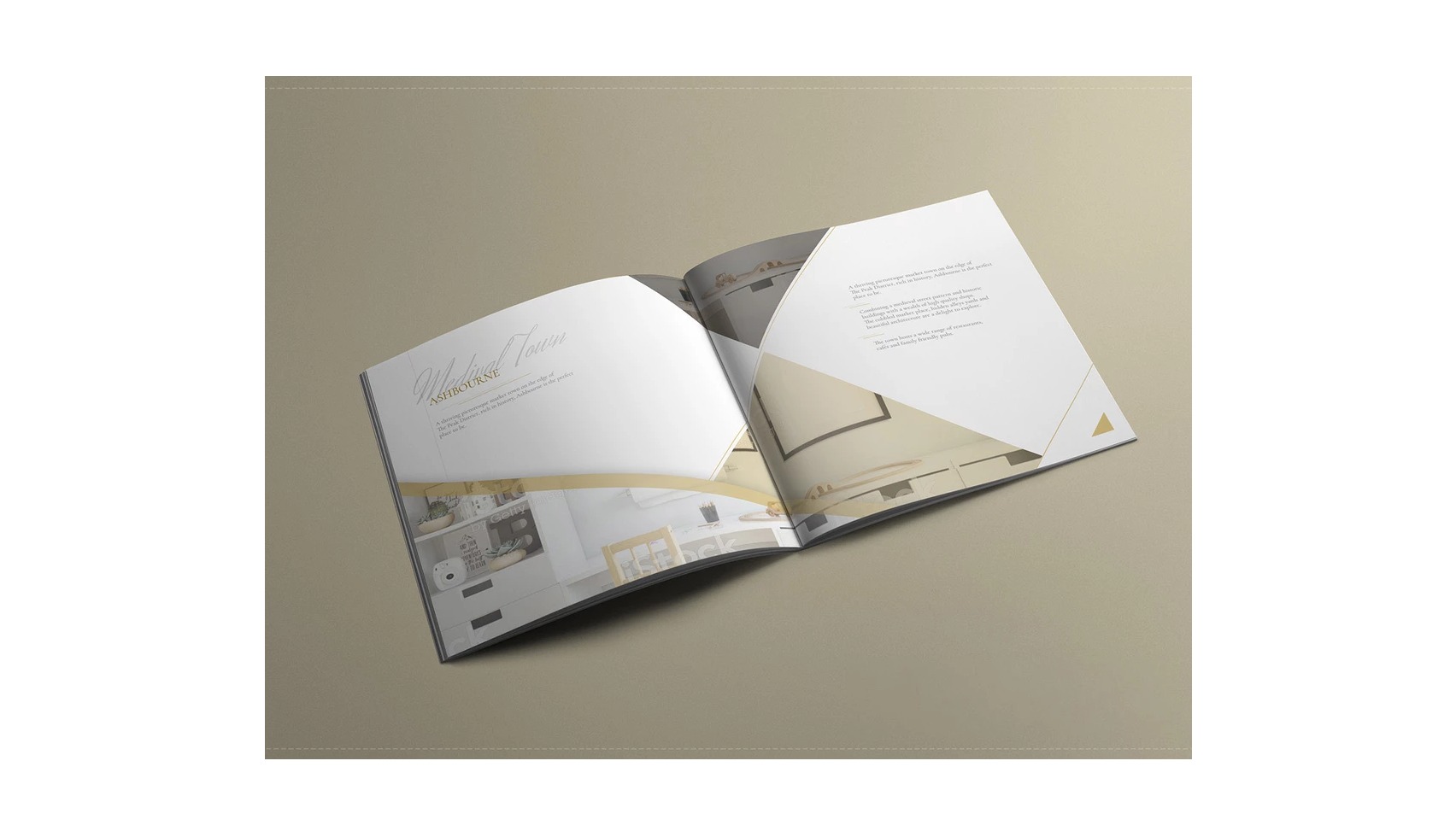Otwarta broszura reklamowa z wizualizacją nowoczesnego wnętrza, z elementami złota na białym tle, leżąca na beżowym tle.