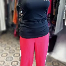 Czarny top sportowy z logo i r&oacute;żowe spodnie dresowe z białym paskiem na manekinie w sklepie z odzieżą.