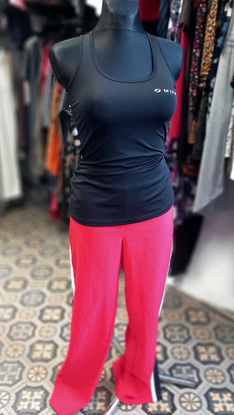 Czarny top sportowy z logo i różowe spodnie dresowe z białym paskiem na manekinie w sklepie z odzieżą.