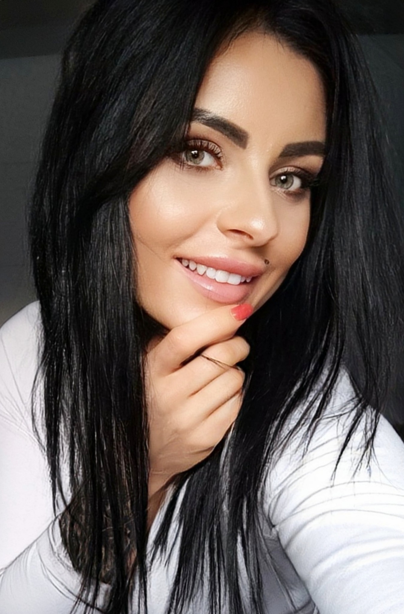 Portret uśmiechniętej kobiety z ciemnymi włosami i delikatnym makijażem, z pierścionkiem na palcu, wykonany w Zielonej Górze.