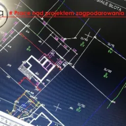 Ekran monitora wyświetlający szczegółowy plan zagospodarowania terenu z naniesionymi wymiarami działek i budynków, w tle widoczne logo firmy projektowej.