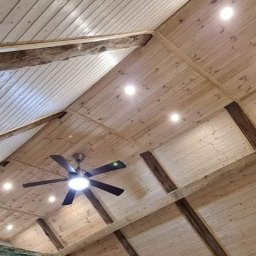 Firma usługowa MARFI - Drewniany sufit z odsłoniętymi belkami, wbudowanymi lampami punktowymi i wentylatorem sufitowym.