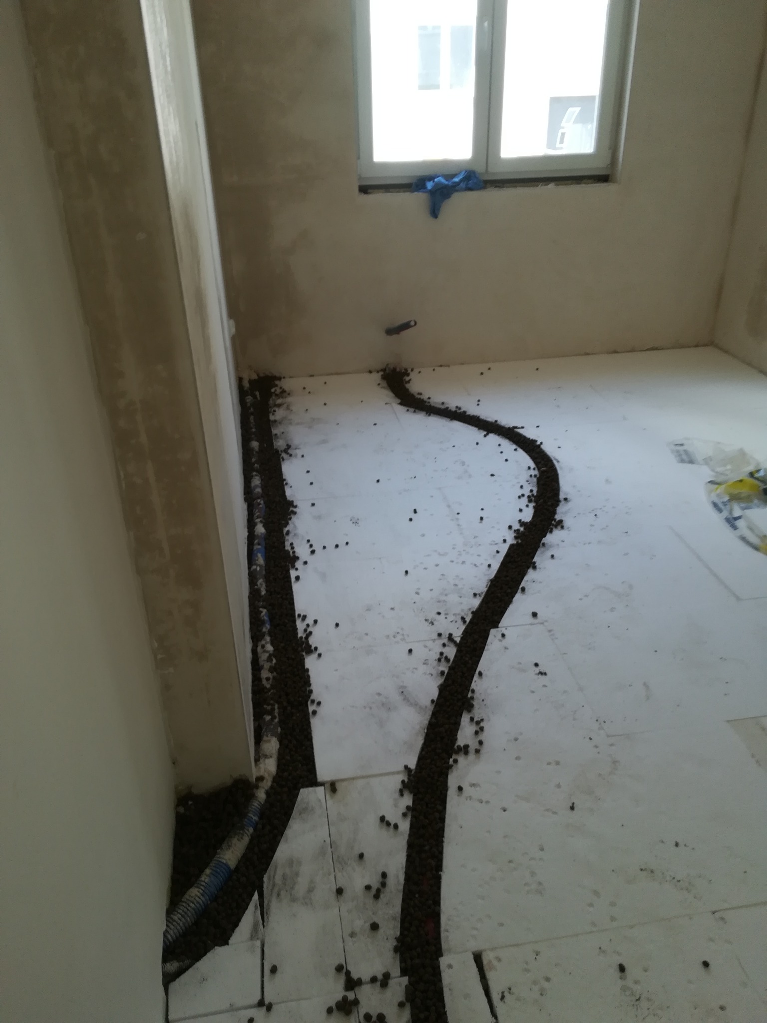 Przygotowanie podłoża pod ogrzewanie podłogowe: rury grzewcze ułożone w warstwie izolacji, obsypane granulatem.