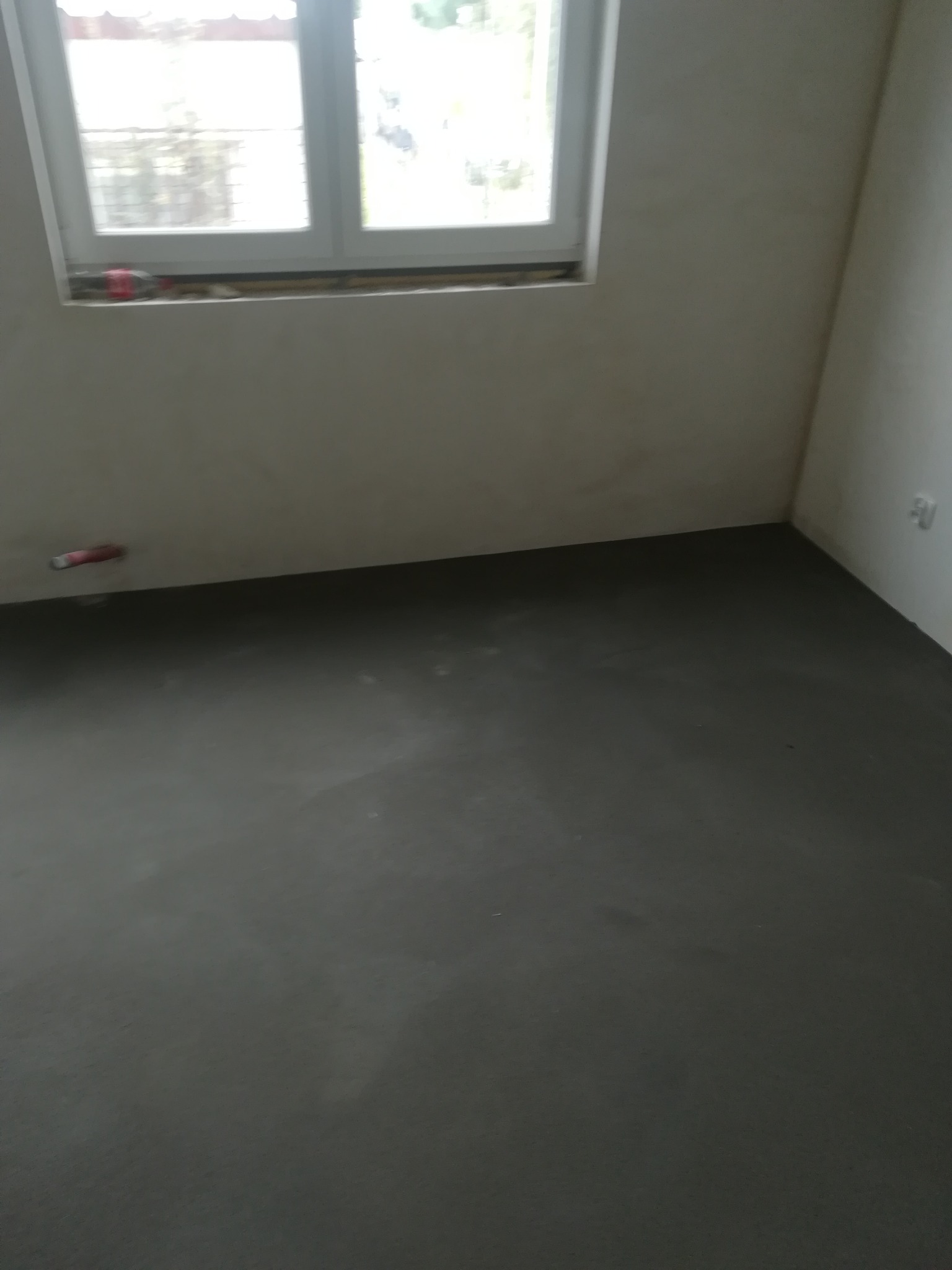 Świeżo wylana, gładka posadzka jastrychowa w jasnym pomieszczeniu z oknem, widoczne ślady po narzędziach.