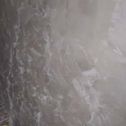 Ściana z efektem dekoracyjnym w odcieniach beżu i bieli, widoczne puszki z farbą w dolnym rogu.