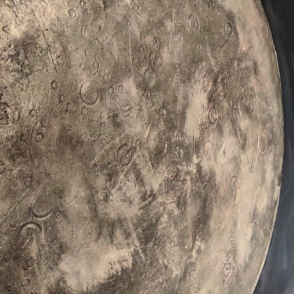 Szpachlowana ściana z efektem kraterów księżycowych w odcieniach szarości, widoczne nieregularne tekstury i cieniowania.