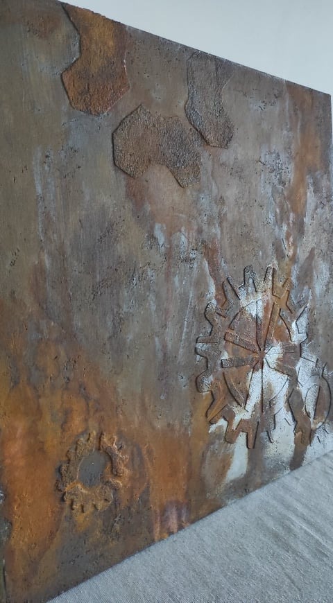 Dekoracyjna ściana z fakturą rdzy i wytłoczonymi elementami w kształcie zębatek, widziana pod kątem.