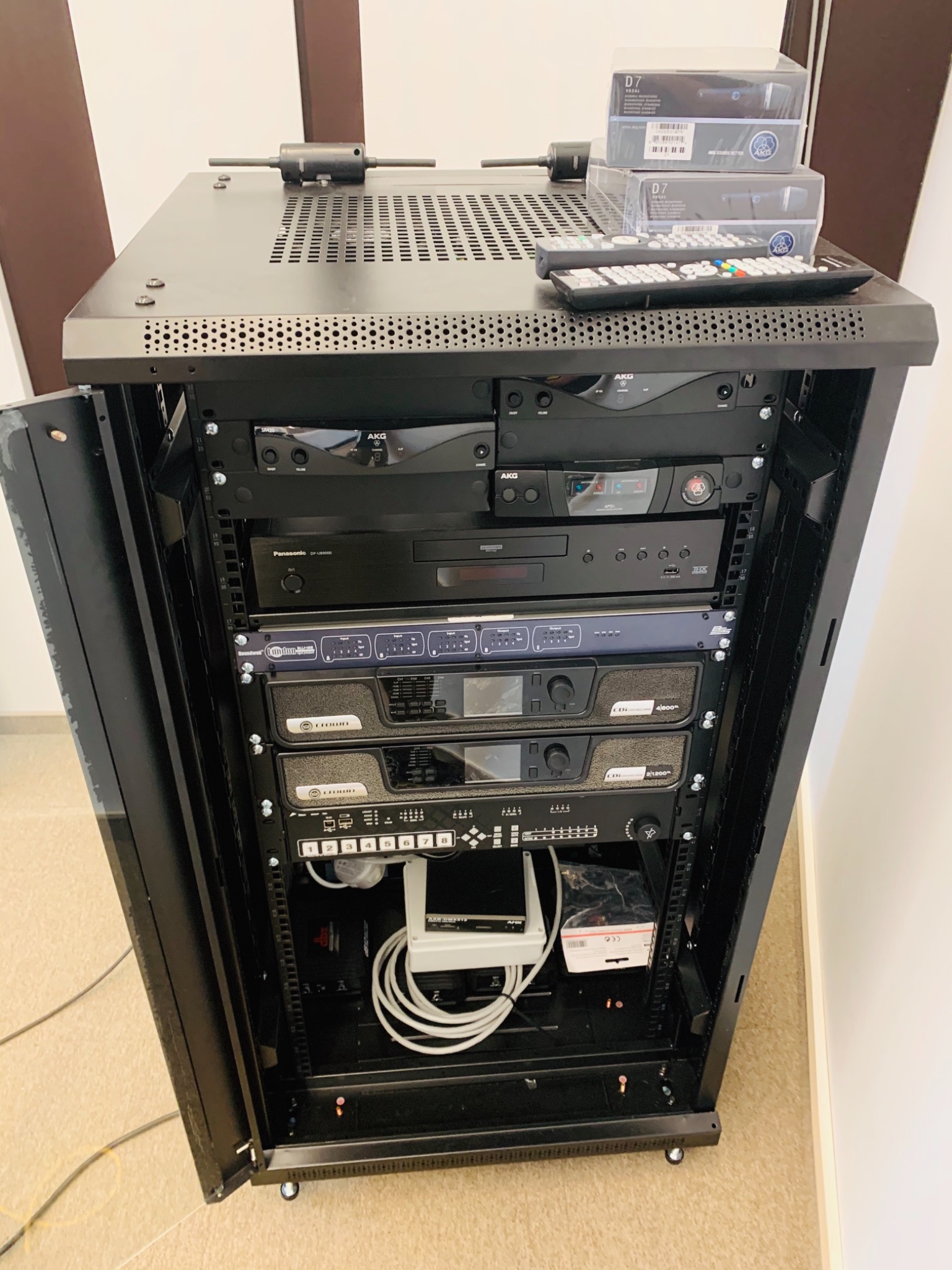 Szafa rack z zamontowanym sprzętem audio, w tym wzmacniacze Crown, odtwarzacz Panasonic, mikrofony AKG D7 w pudełkach i pilot, zainstalowana przez firmę z Lubina.