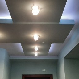 Dariusz Stasiak firma uslugowo-remontowa - Nowoczesny sufit podwieszany z wbudowanym oświetleniem punktowym, tworzący geometryczny wzór na tle jasnych ścian.