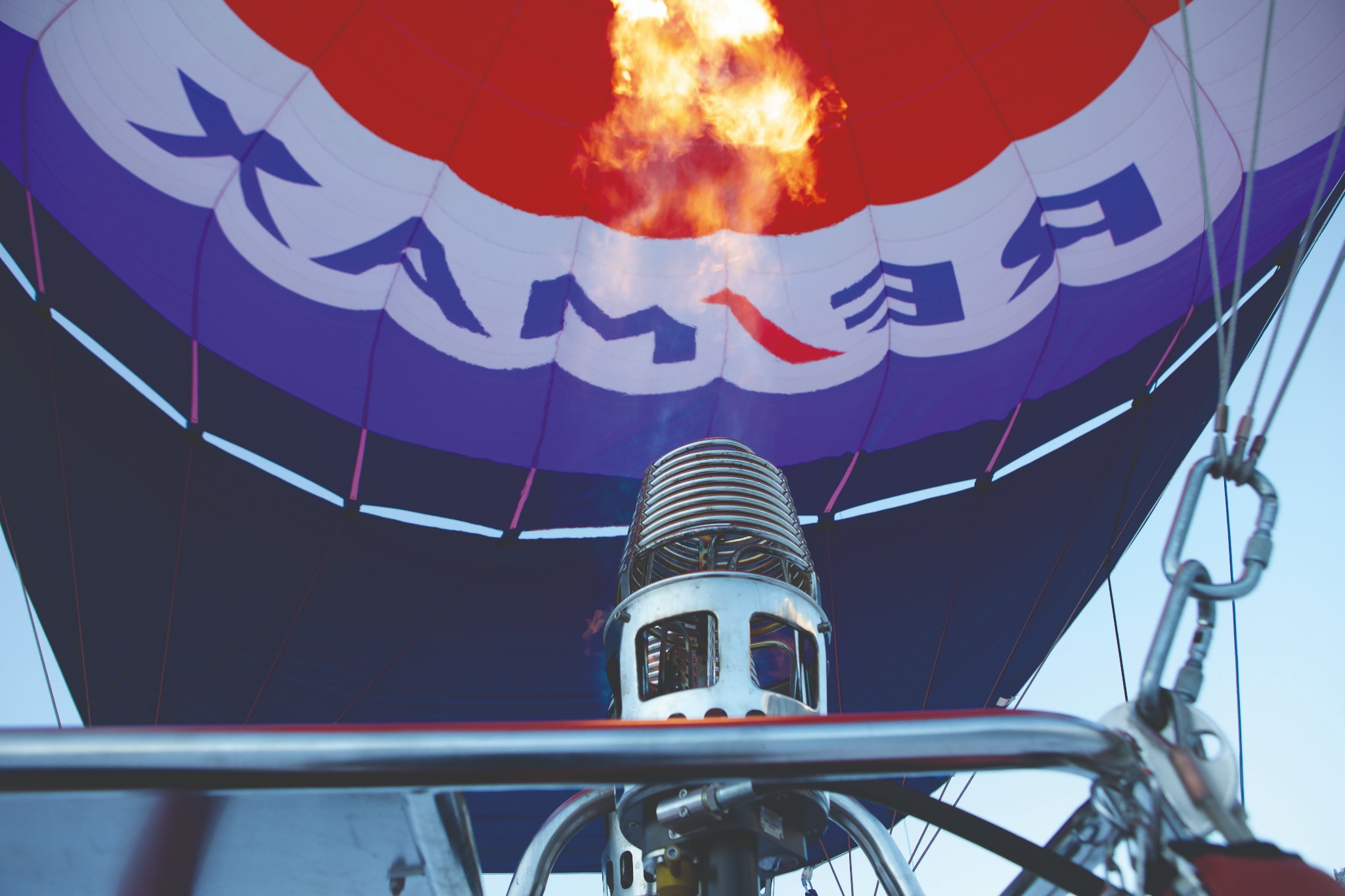 Wnętrze balonu na ogrzane powietrze z palnikiem w trakcie pracy, widoczne wzory na powłoce i elementy konstrukcyjne.