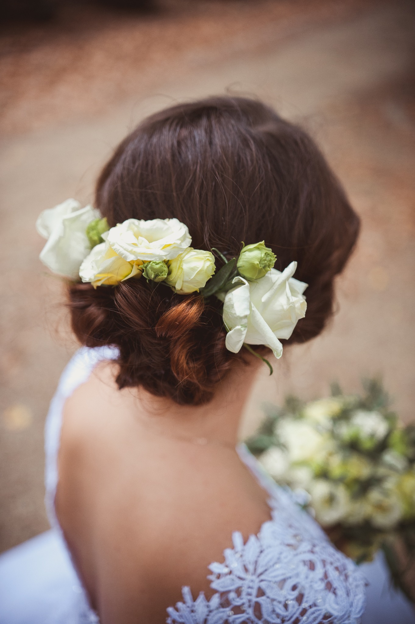 Upięcie ślubne z wiankiem z białych róż i eustomy, widok z tyłu na koronkową suknię i bukiet ślubny.