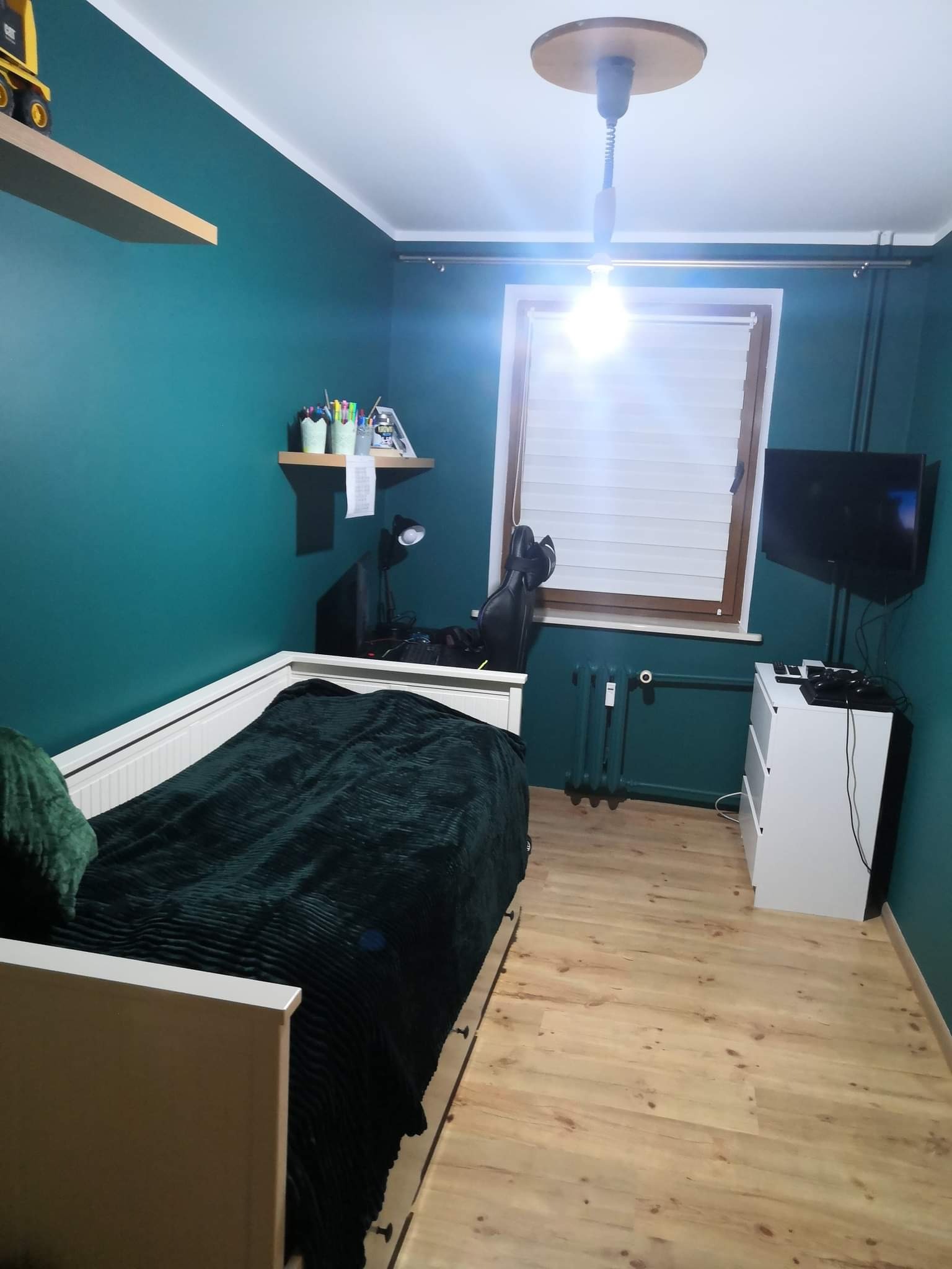 Pokój młodzieżowy po odświeżeniu, ściany pomalowane na ciemny turkus, drewniana podłoga, białe meble i drewniane elementy dekoracyjne