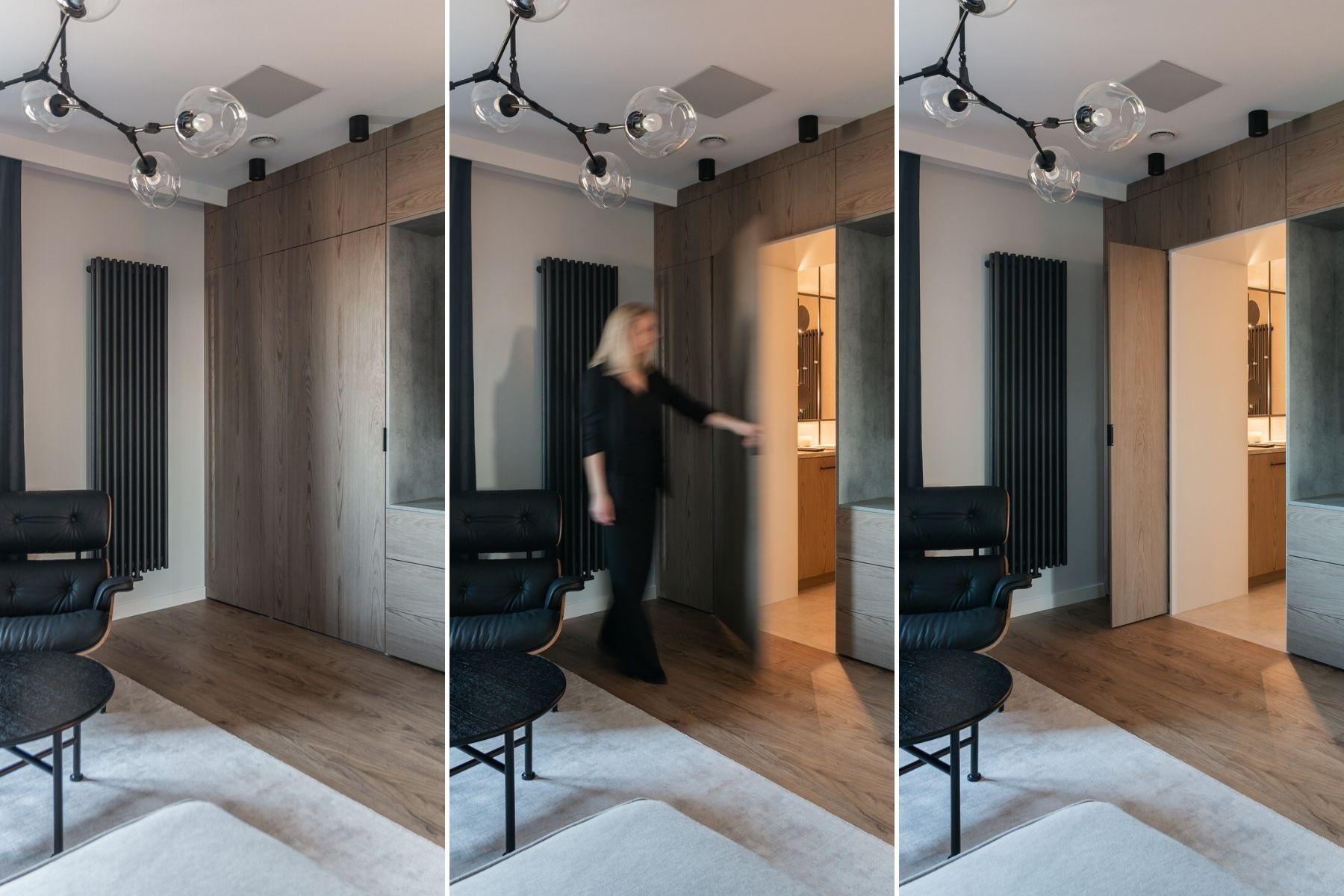 Nowoczesna sypialnia z ukrytymi drzwiami do łazienki, widoczna czarna skórzana sofa, grzejnik żeberkowy i lampa sufitowa z szklanymi kulami, kobieta otwiera drzwi do łazienki.