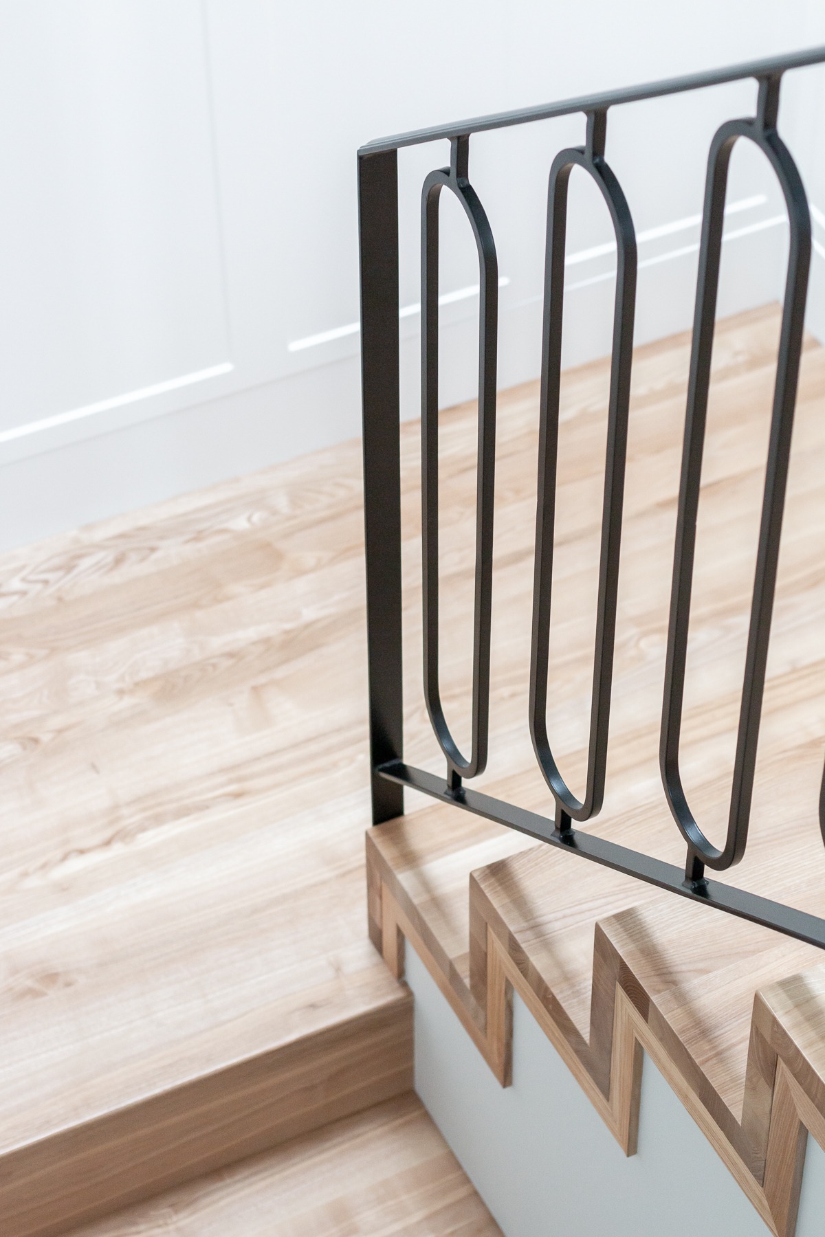 Nowoczesne schody z drewnianymi stopniami i czarną, metalową balustradą o minimalistycznym designie, widoczne z góry.