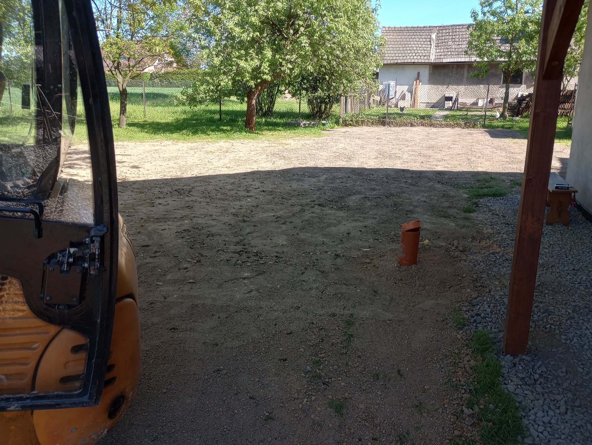 Przygotowany teren pod budowę z widocznym fragmentem maszyny budowlanej, rurą PCV i drewnianą konstrukcją z boku.