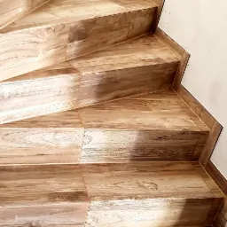 Wyłożone drewnopodobnymi płytkami schody wewnętrzne, widok z dołu na górę, z bliska, fuga w kolorze płytek.