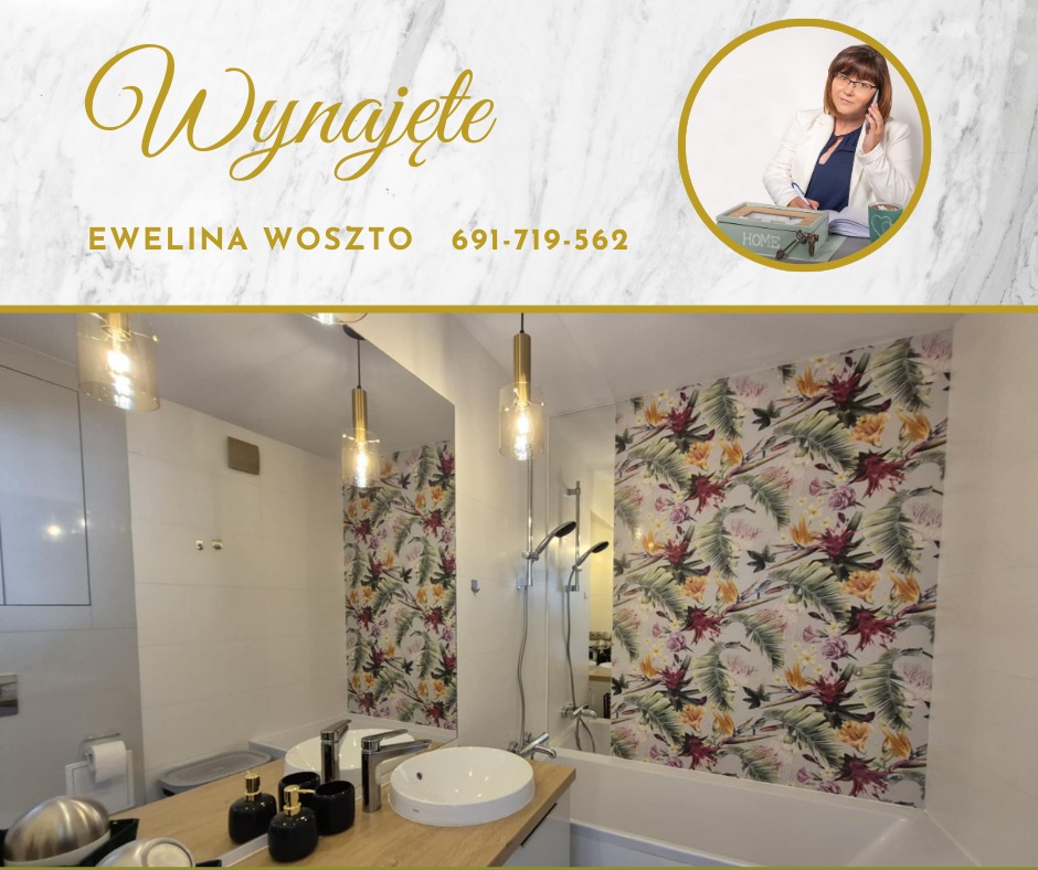 Wykończona łazienka z tropikalną tapetą, umywalką i złotymi lampami. U góry napis 'Wynajęte' i zdjęcie agentki nieruchomości Eweliny Woszto.