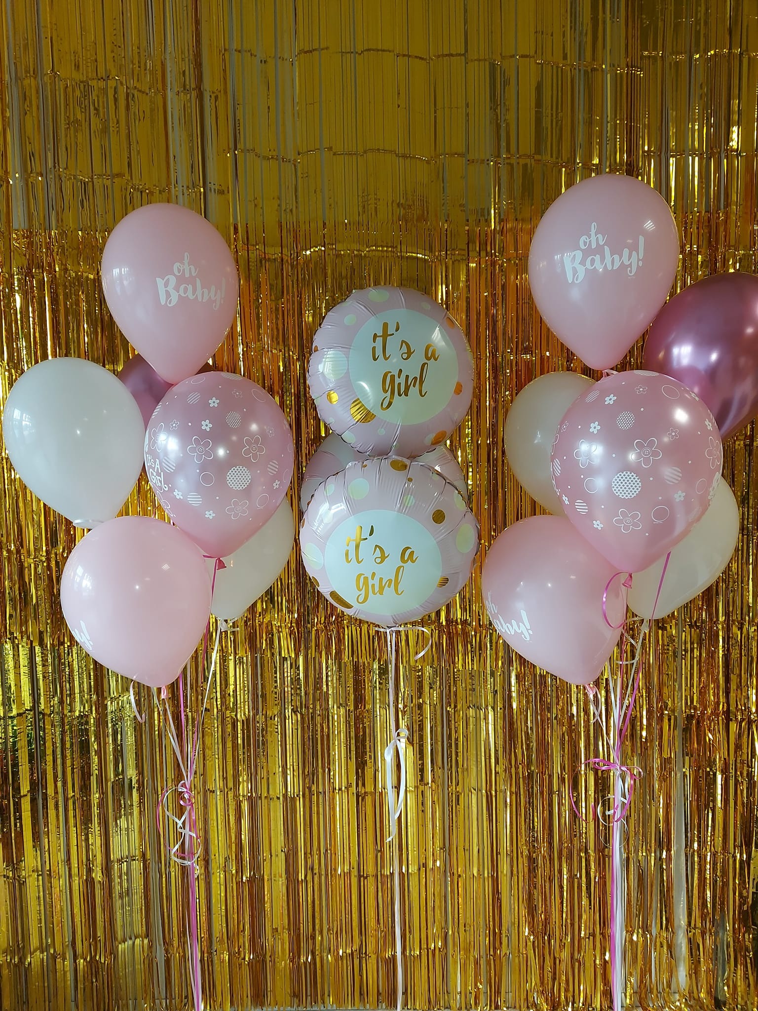 Dekoracja balonowa na baby shower dziewczynki: różowe i białe balony z napisem 'Oh Baby!' i 'It's a girl' na złotym, błyszczącym tle.