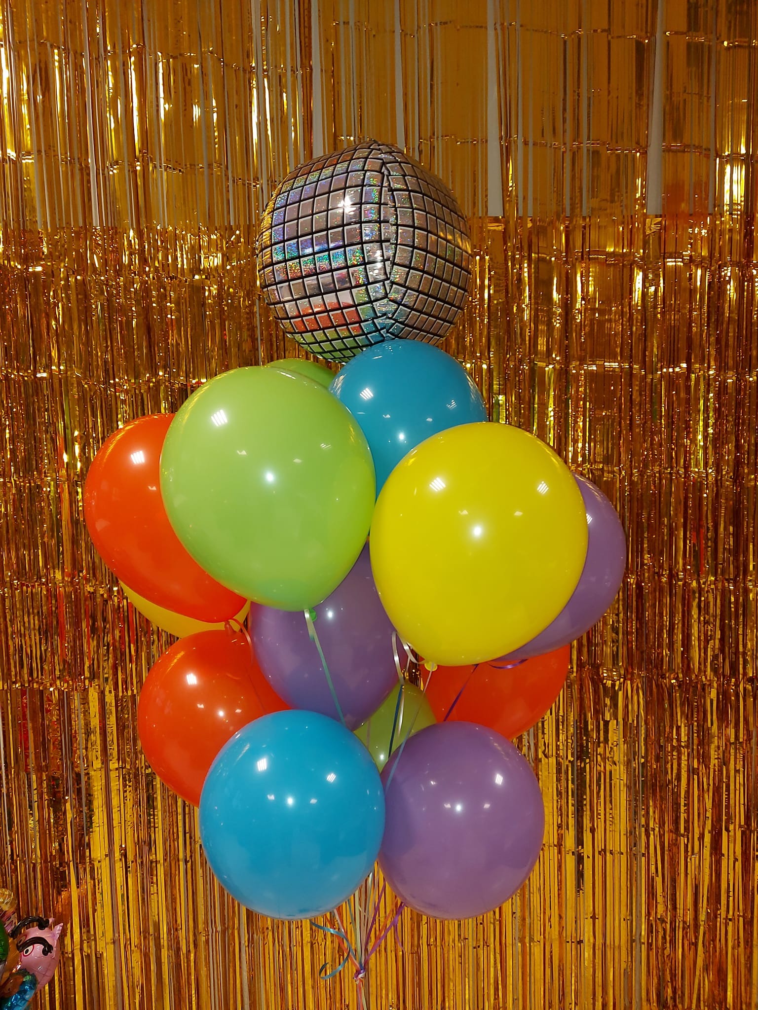 Bukiet kolorowych balonów z dyskotekową kulą na złotym, błyszczącym tle.