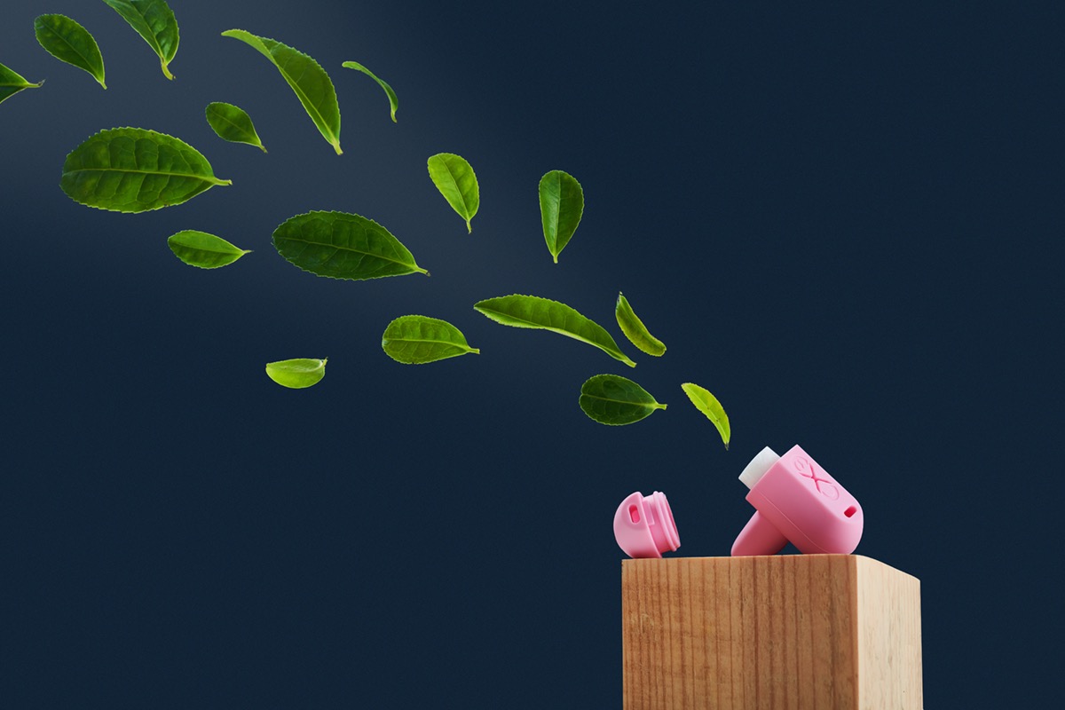 Latające zielone liście i różowy, zabawkowy suszarka do włosów na drewnianym bloku na ciemnoniebieskim tle.