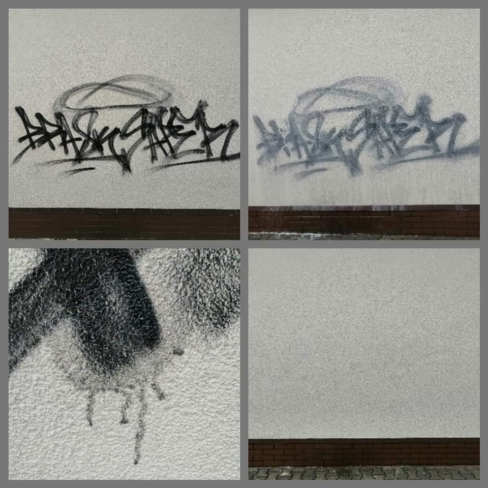 Elewacja budynku z szarą graffiti i zaciekami, widok na fragment ściany z ceglanym cokołem.