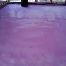 Równa, świeżo nałożona, różowa izolacja piankowa na podłodze pomieszczenia w Wólce Pełkińskiej. Czarny worek na śmieci stoi przy oknie.