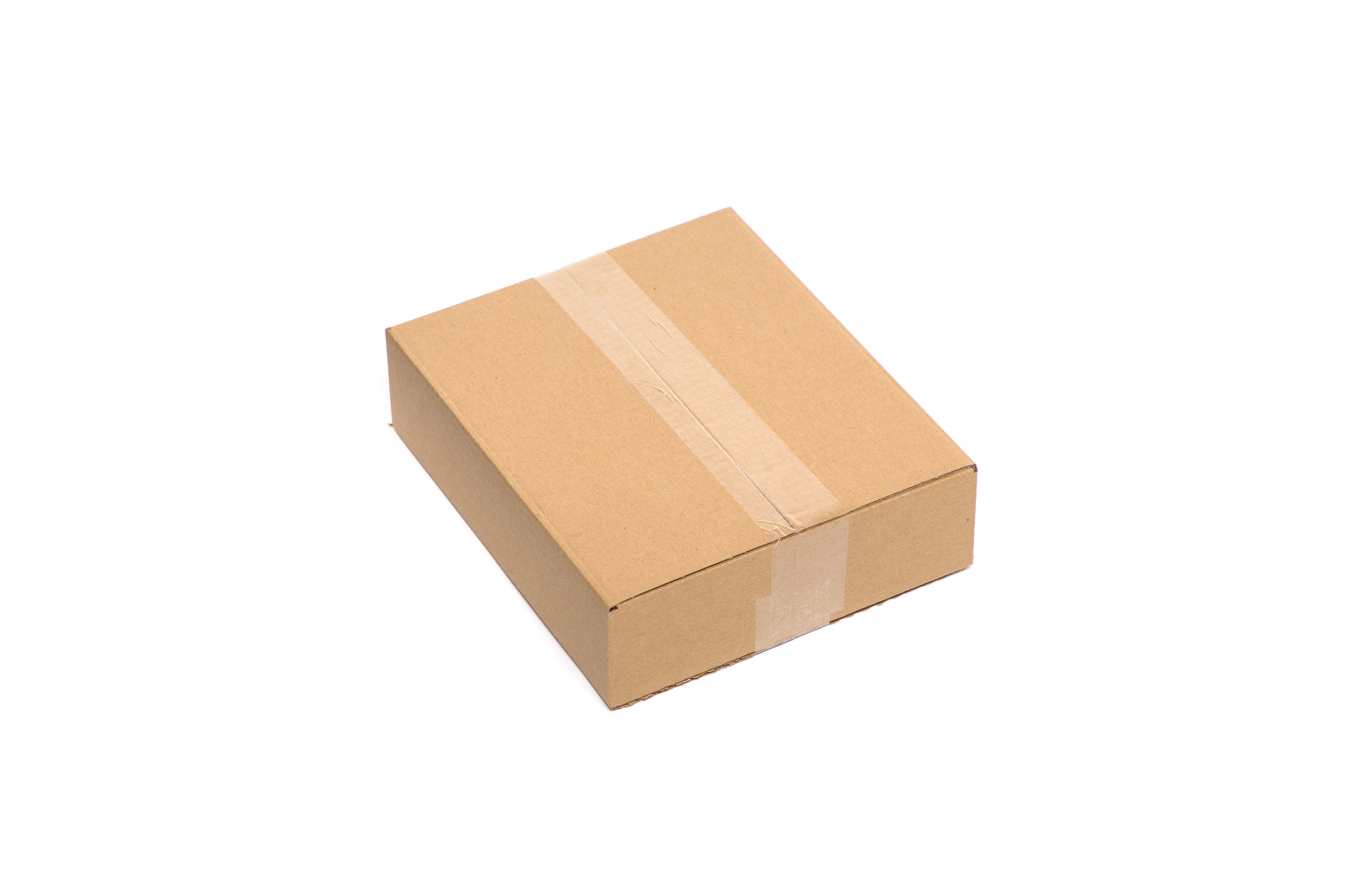 Zamknięte, puste pudełko z brązowej tektury falistej, zabezpieczone przezroczystą taśmą klejącą, leżące ukośnie na białym tle.