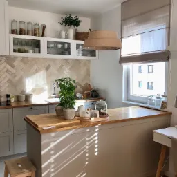 Beżowa, rzymska osłona okienna w jasnej kuchni z drewnianym blatem i dekoracyjnymi pojemnikami na półkach.