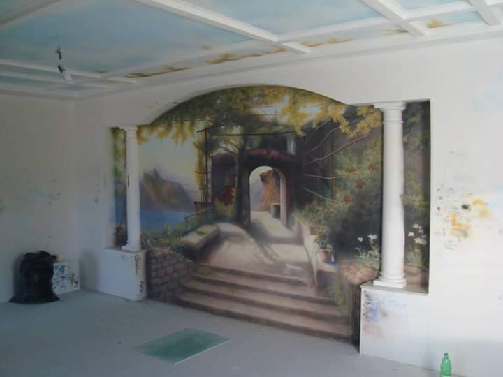 Malowidło ścienne imitujące toskański krajobraz z kolumnami, widoczne ślady po rozpylonym farbie na ścianie, malowany sufit imitujący niebo.