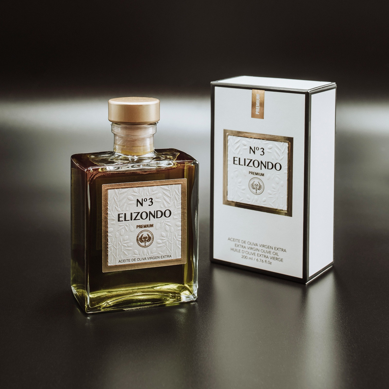 Butelka oliwy z oliwek Elizondo No. 3 Premium obok pudełka na ciemnym tle, prezentacja produktu.